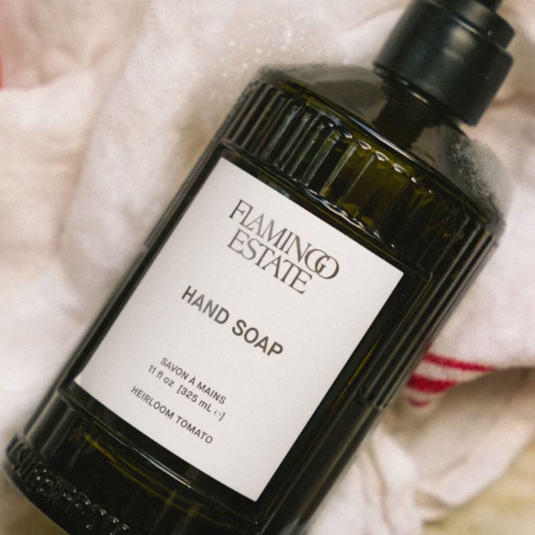 A green glass bottle with a white label lying on a white towel with red stripes