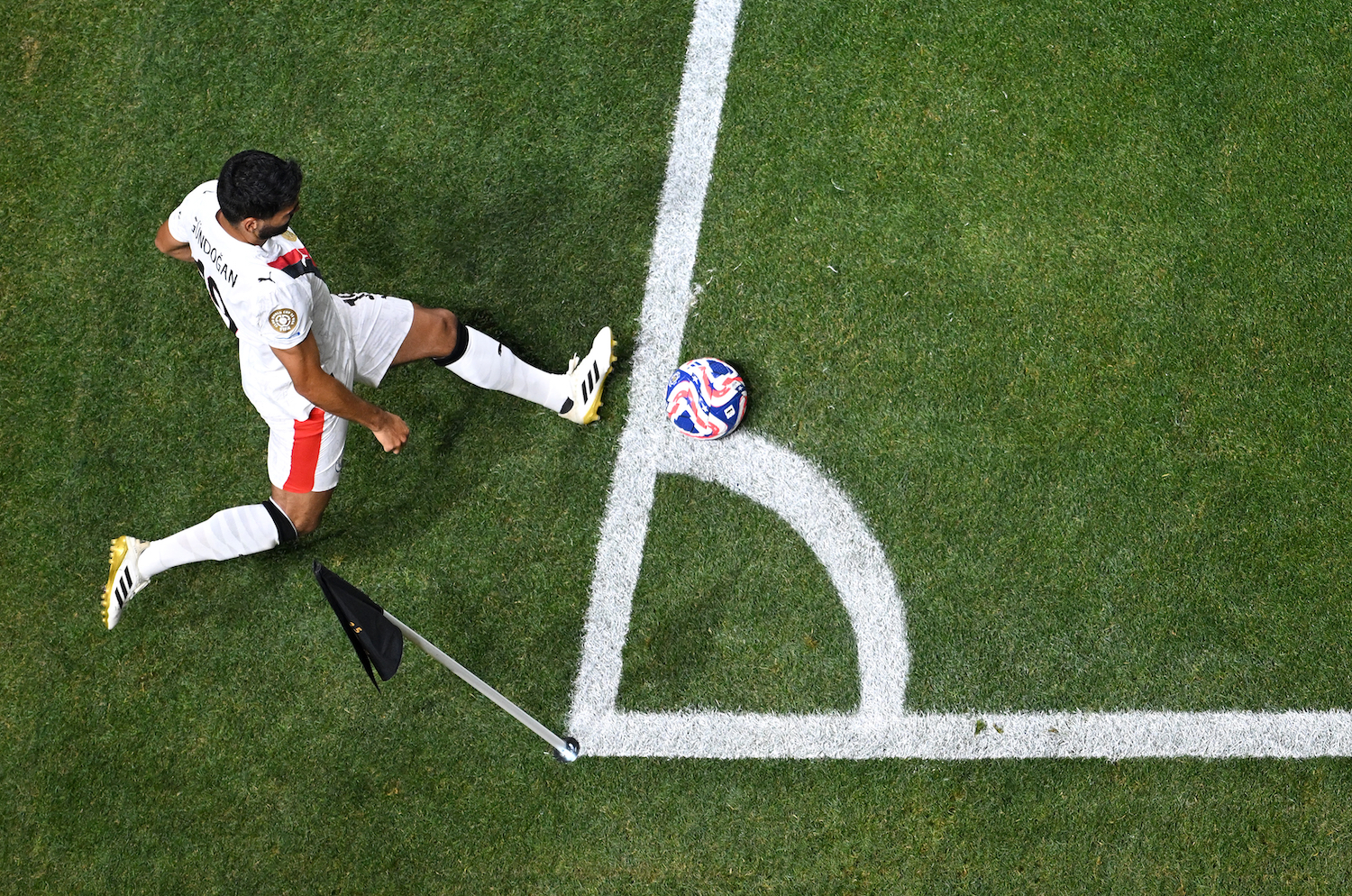 A soccer player performing a corner kick, aerial view.
