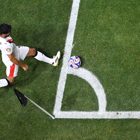 A soccer player performing a corner kick, aerial view.