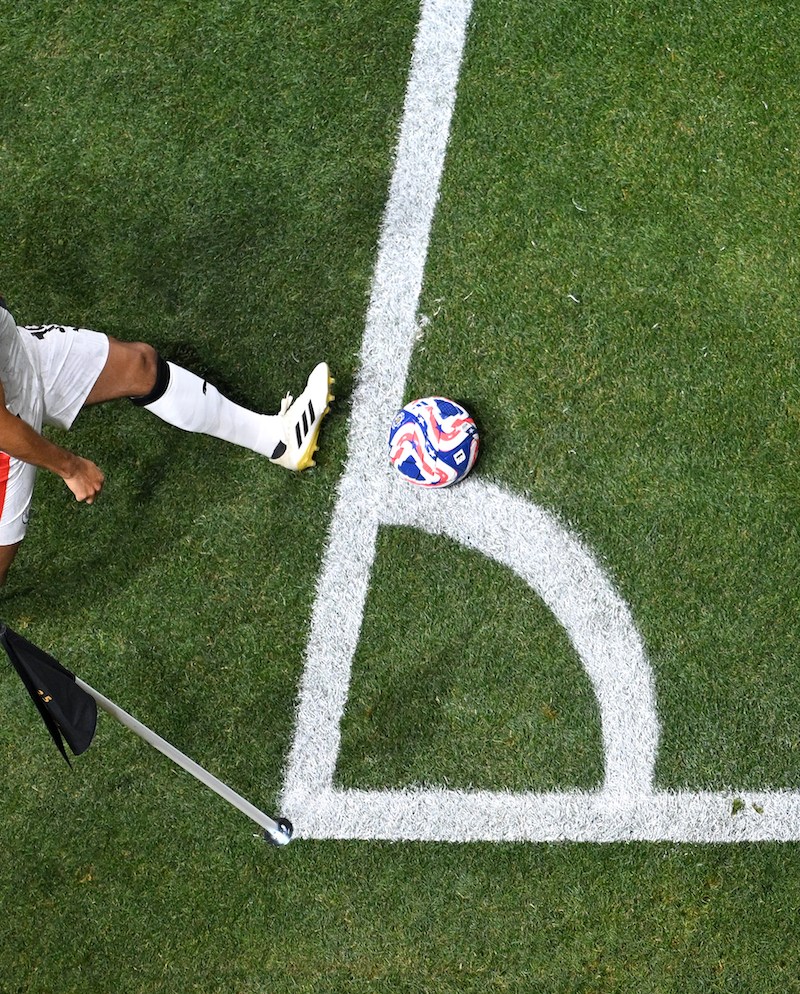 A soccer player performing a corner kick, aerial view.