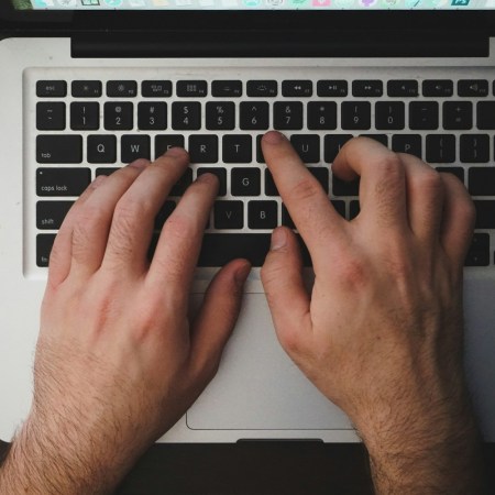 Hands typing on a laptop keyboard