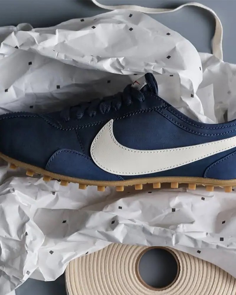 A blue shoe with a white Nike swoosh logo sitting on a piece of crumpled paper