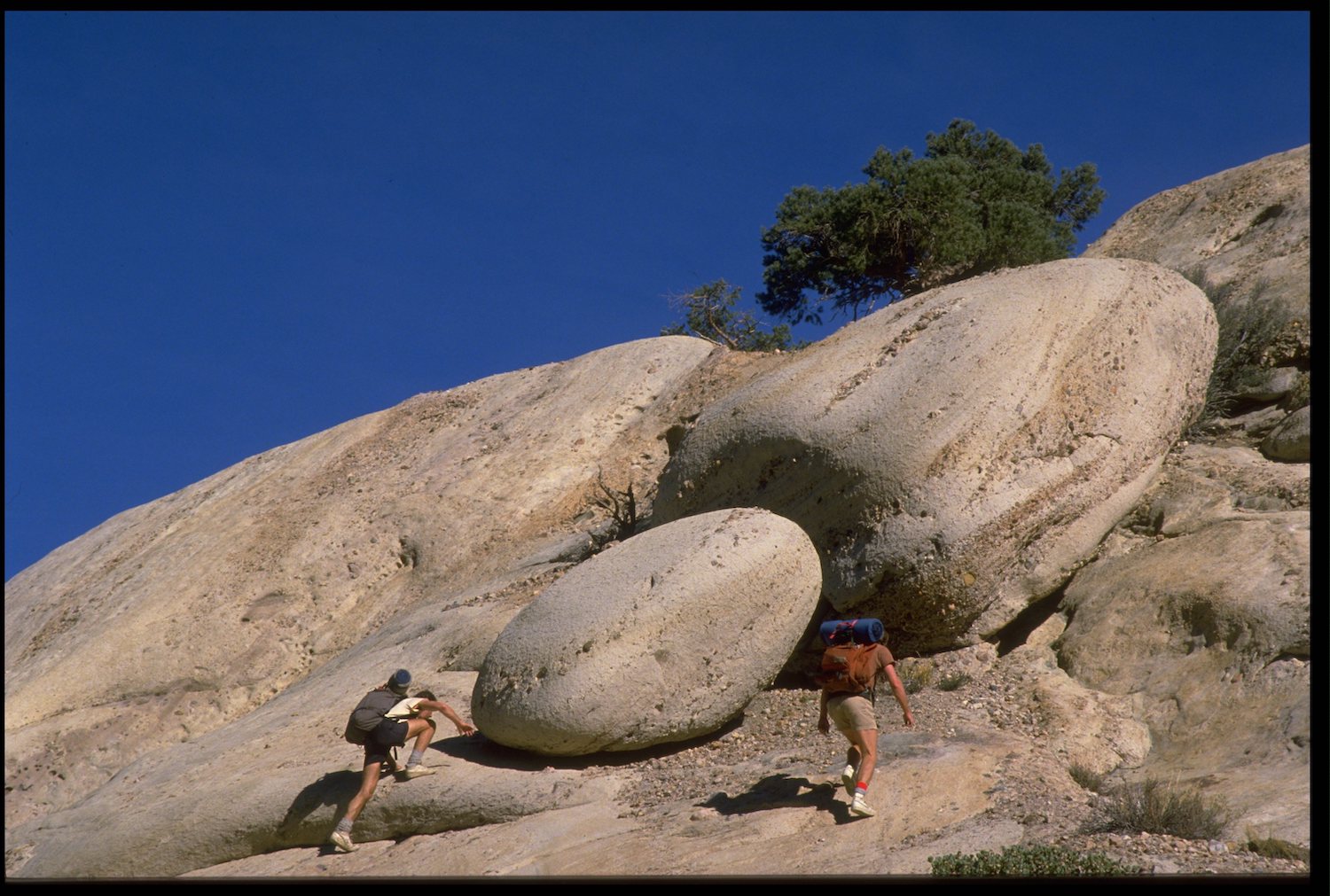 Two men scrambling up rocks.