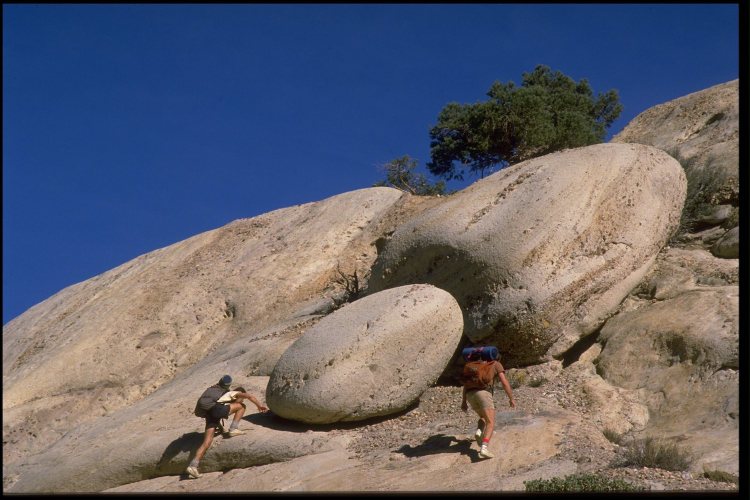 Two men scrambling up rocks.