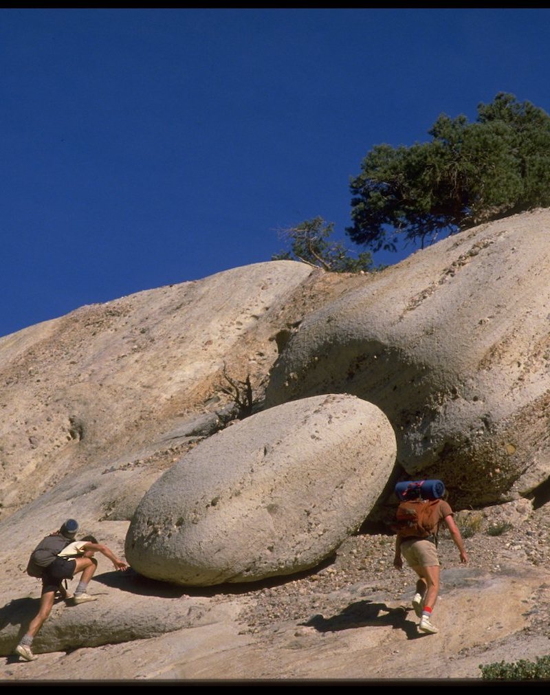 Two men scrambling up rocks.