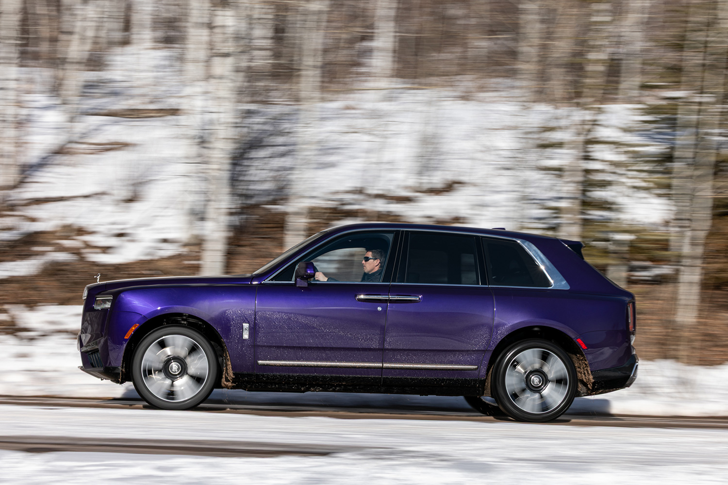 A man driving a purple SUV down a snowy road