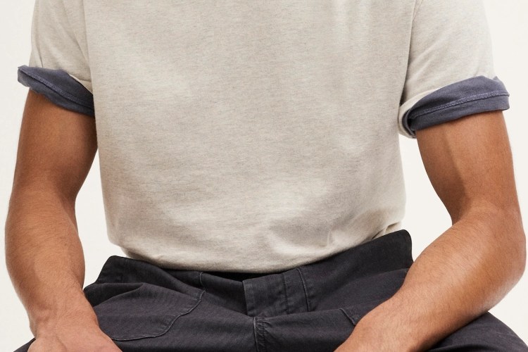 Torso of a person wearing a light gray t-shirt with rolled-up dark gray sleeves and dark gray pants.