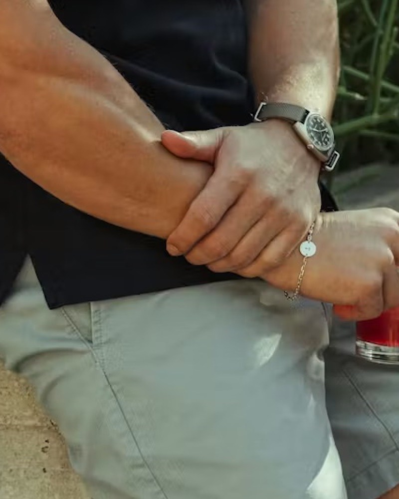 A man holding a drink outside in tan shorts