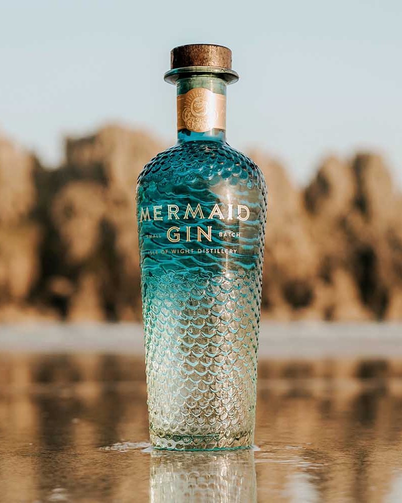 Mermaid Gin bottle on the beach near the ocean water