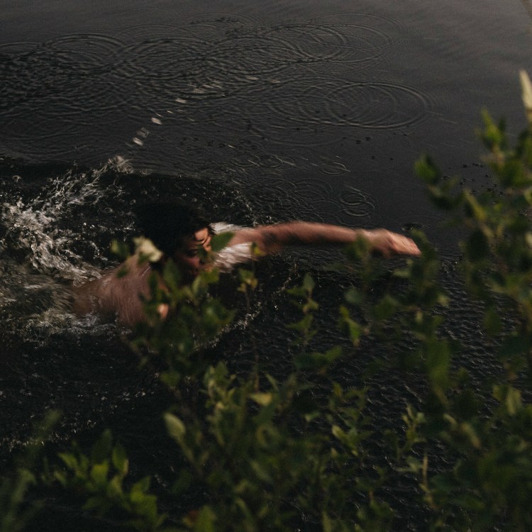 A man swimming in a pond.