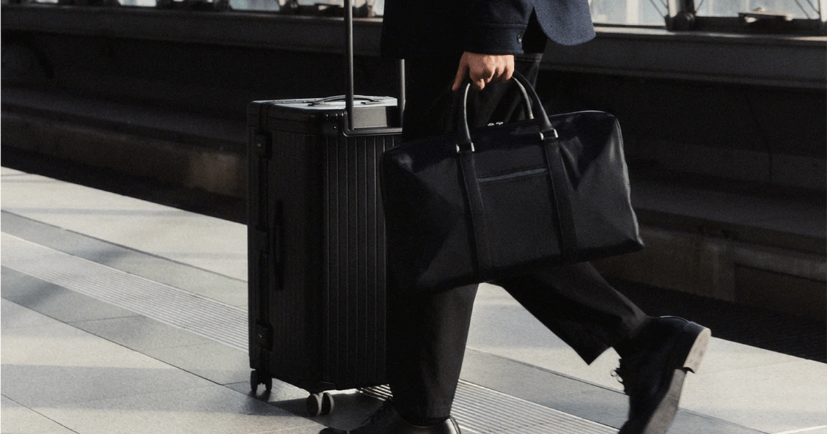Carl Friedrik lifestyle image of man holding weekender bag pushing suitcase