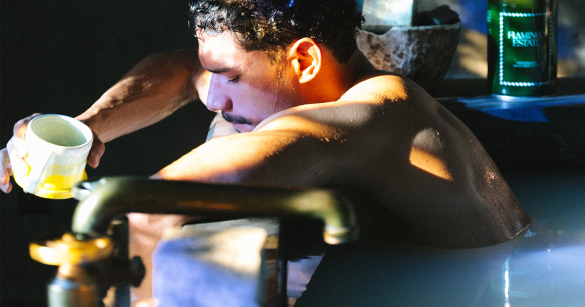 A man sitting in a bath holding a cup of coffee