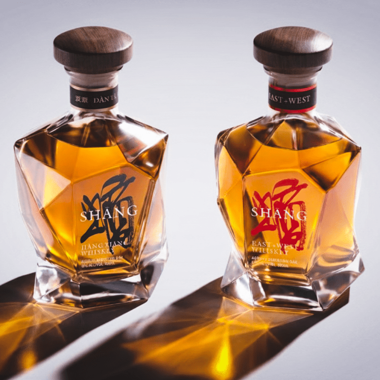 Two bottles of Shang whiskey on a grey background, with shadows