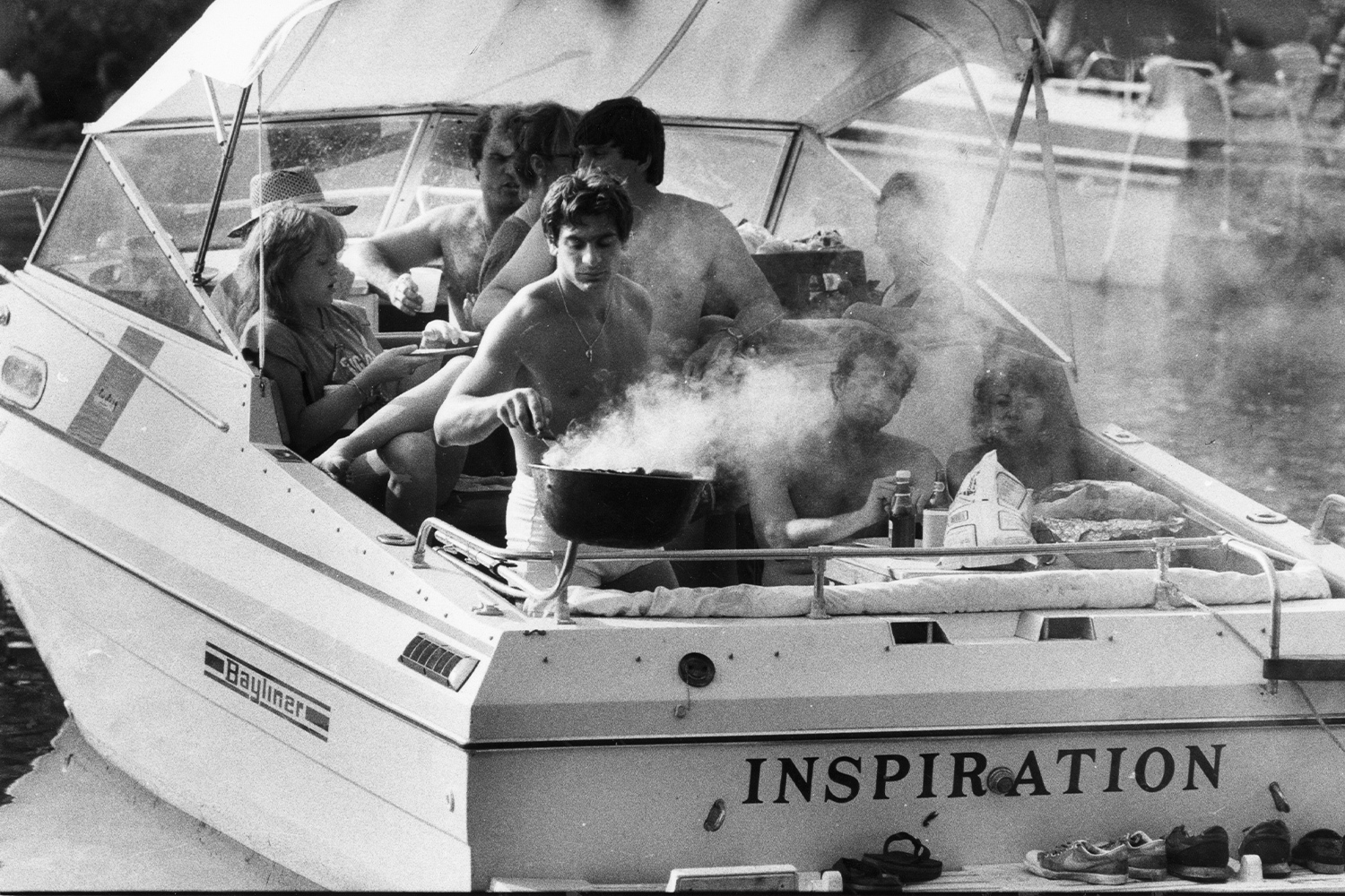 black and white photo of people on a boat with a grill