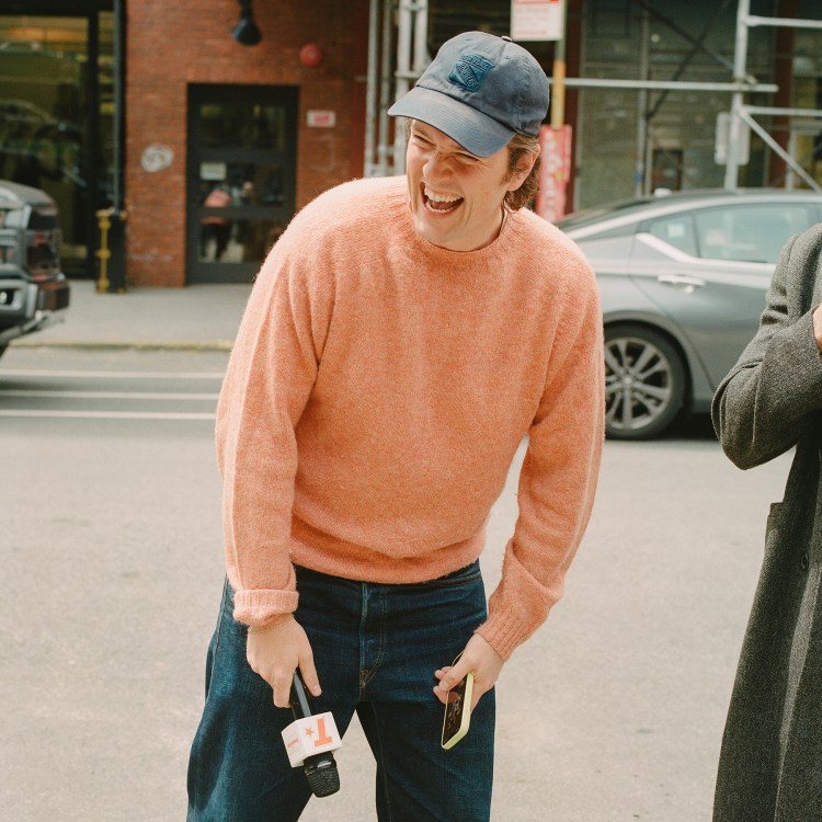 A man in a peach sweater with a New York Rangers baseball cap laughing, with the text "What's in Your Algo?" over the top