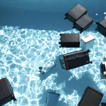 Various pieces of Carl Friedrik luggage floating in a pool