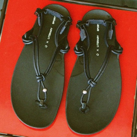 A pair of black roped sandals on a red tray