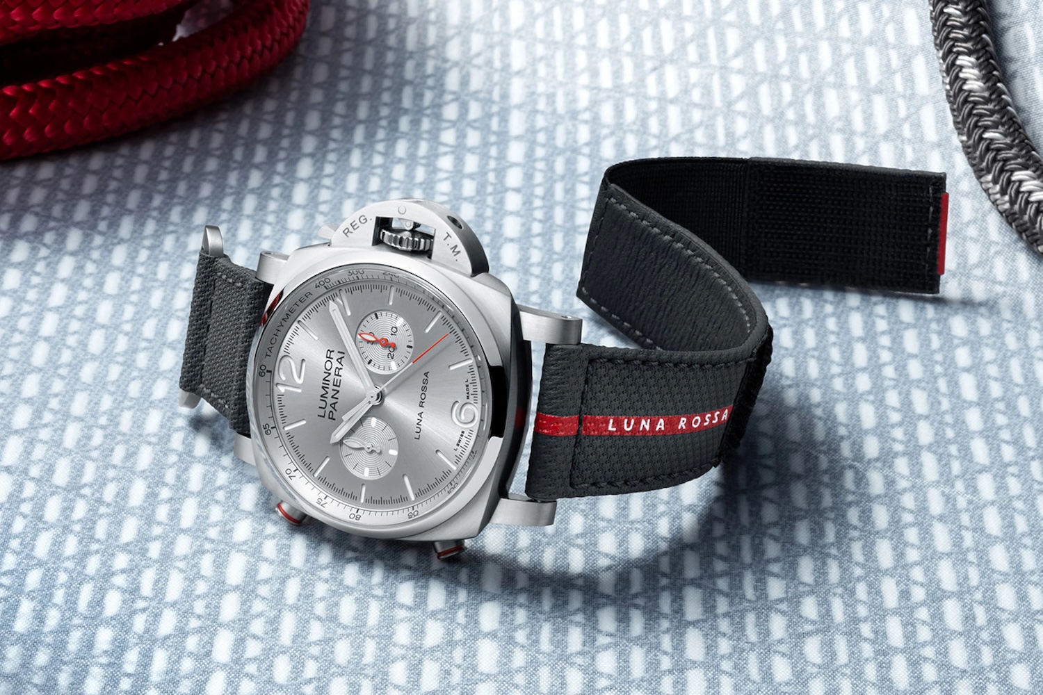 a silver watch with a black and red strap on a table