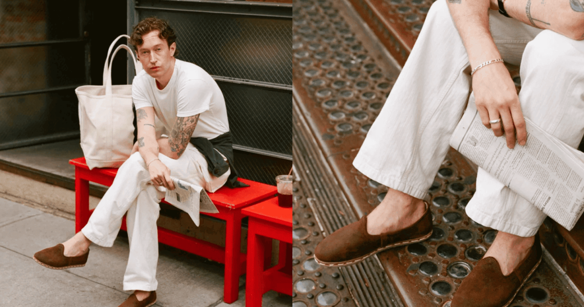 A man sitting with his suede slippers on a red bench.