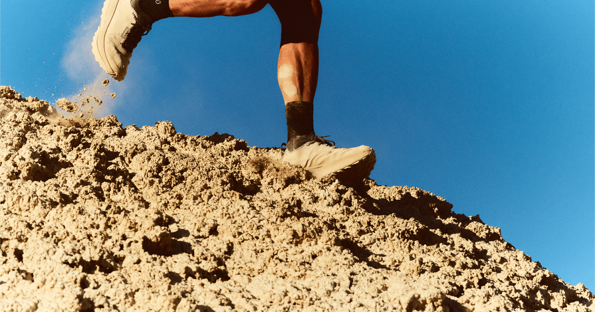 Man running on sandy dune in beige running shoes.