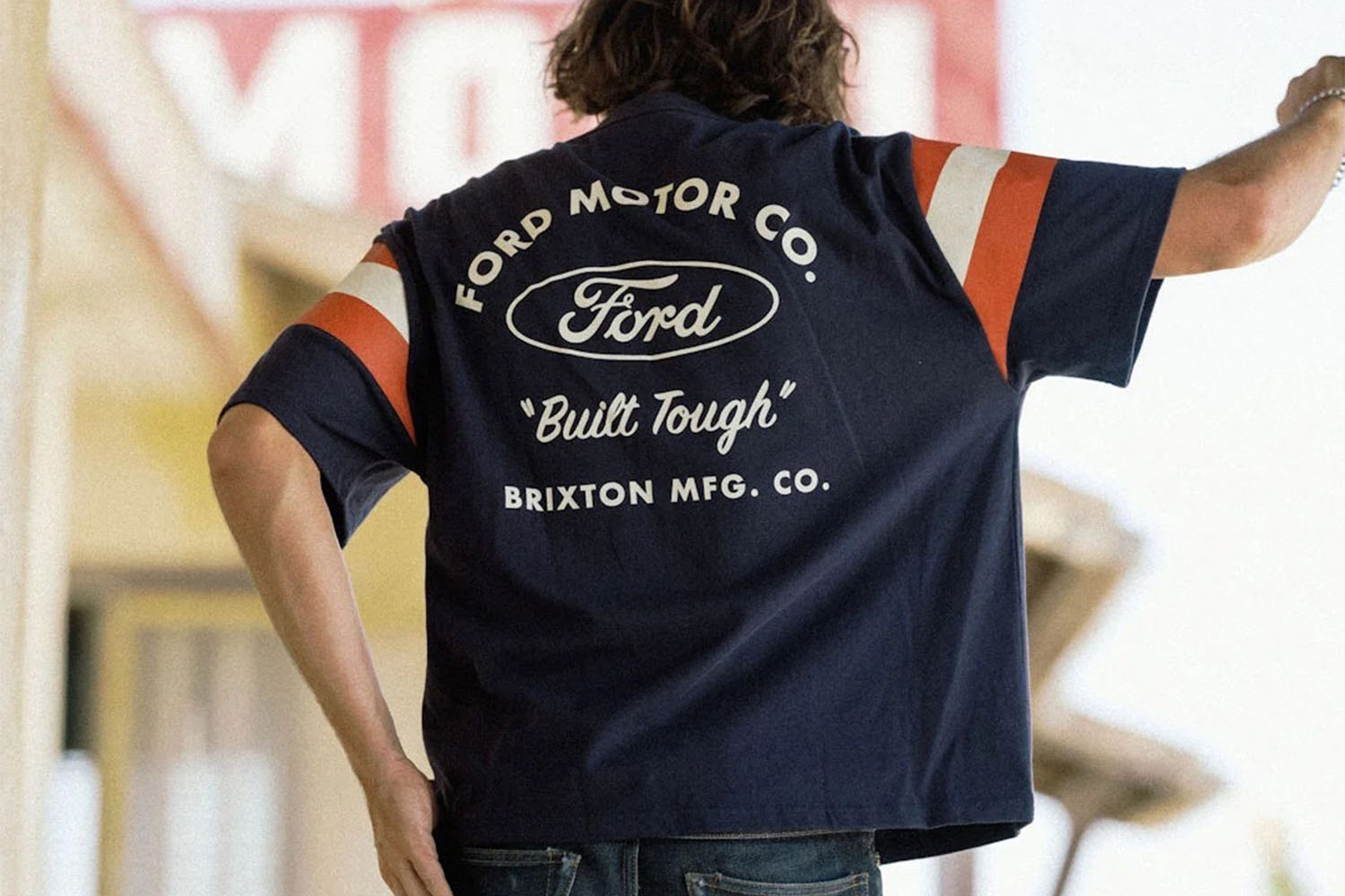 A model in a blue shirt with a Ford x Brixton logo on the back