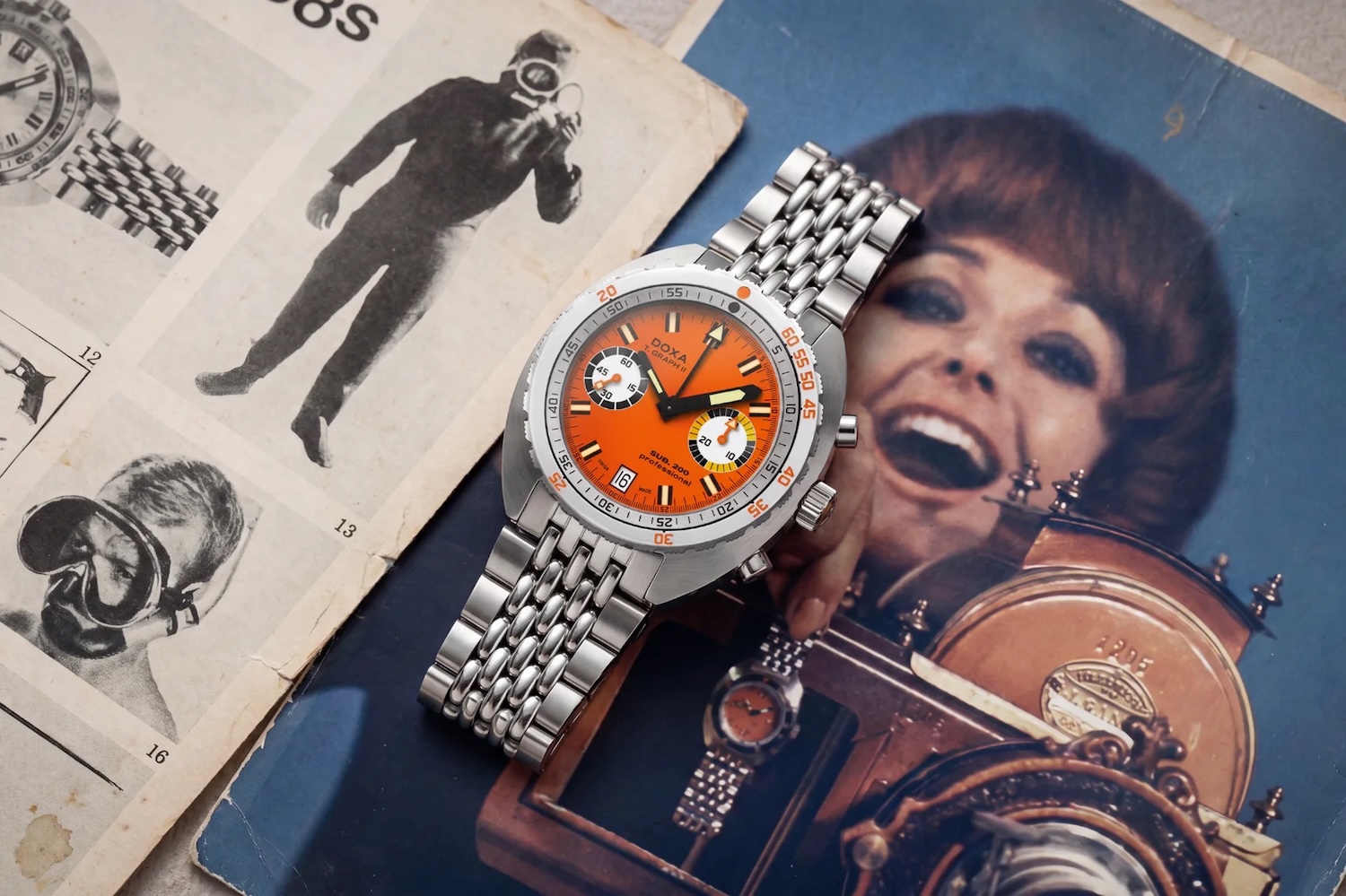 an orange dial Doxa watch on top of old advertisements
