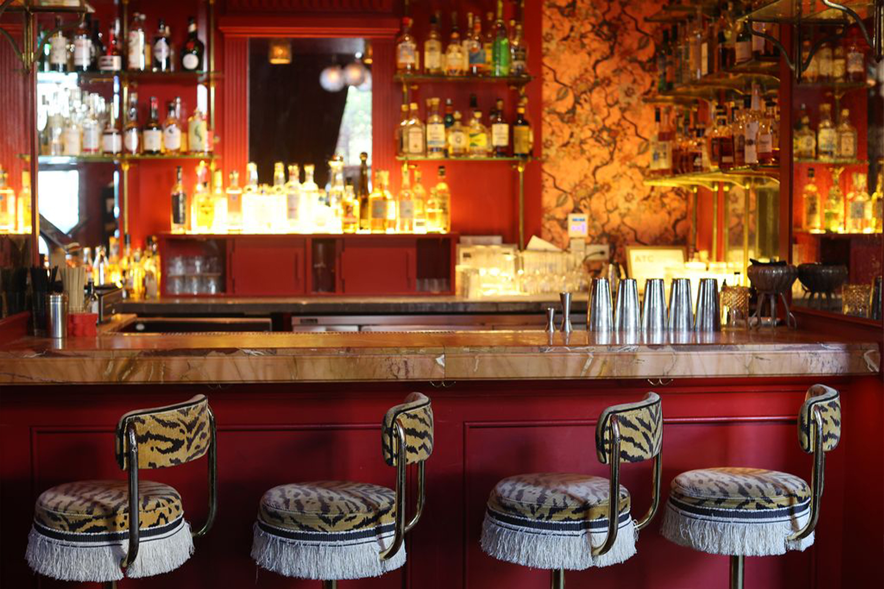 a red bar with four animal print fringed stools in front of it
