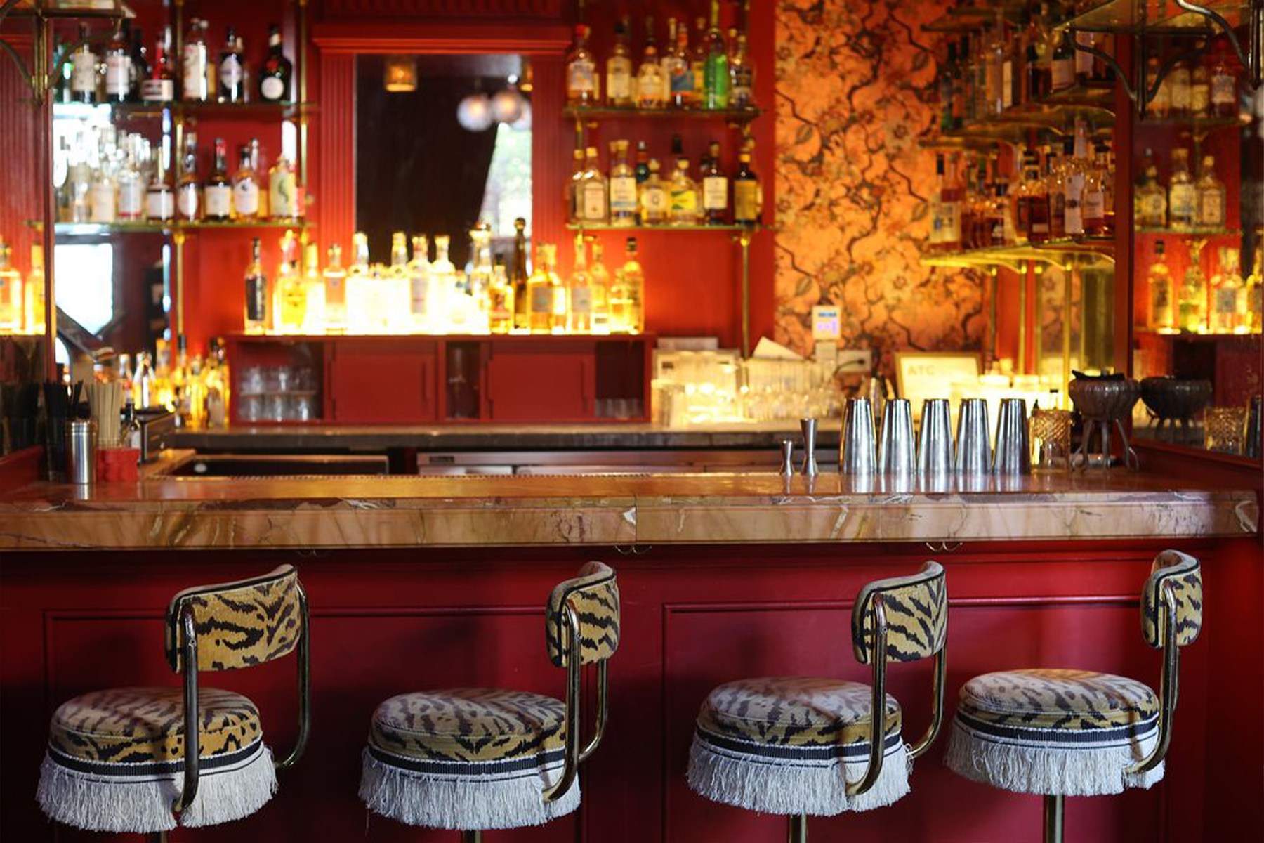 a red bar with four animal print fringed stools in front of it