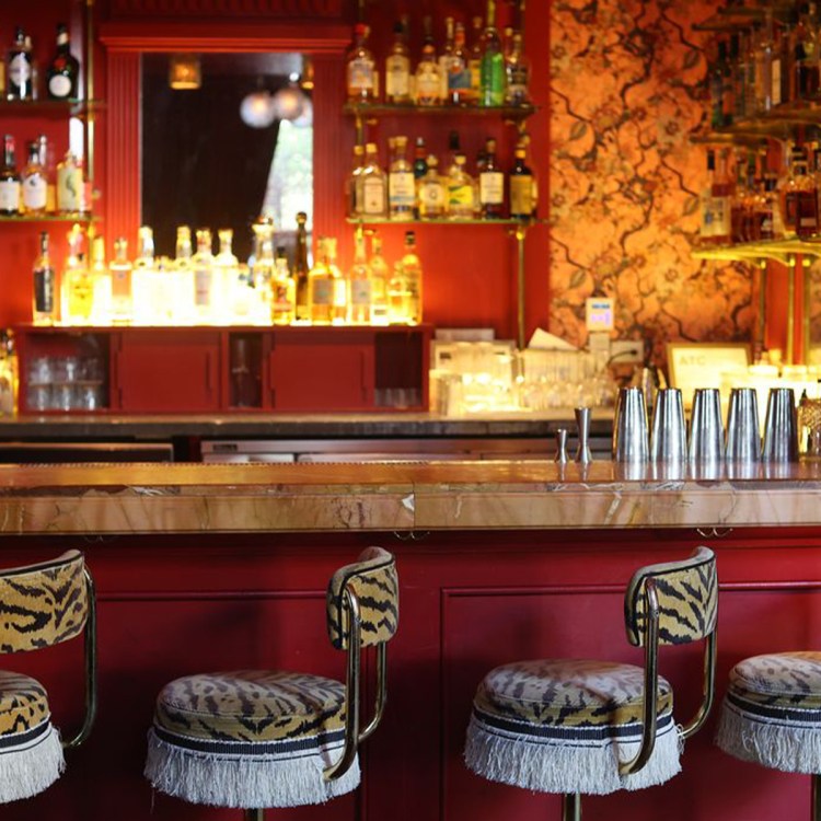 a red bar with four animal print fringed stools in front of it