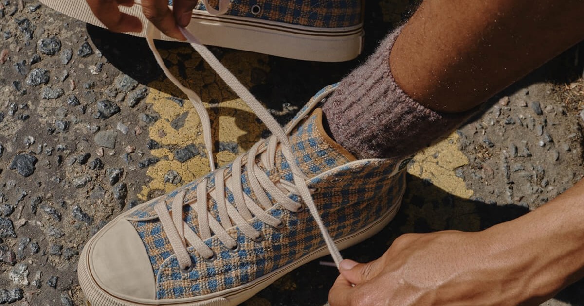 A model tying a pair of brown checked high-top sneakers.
