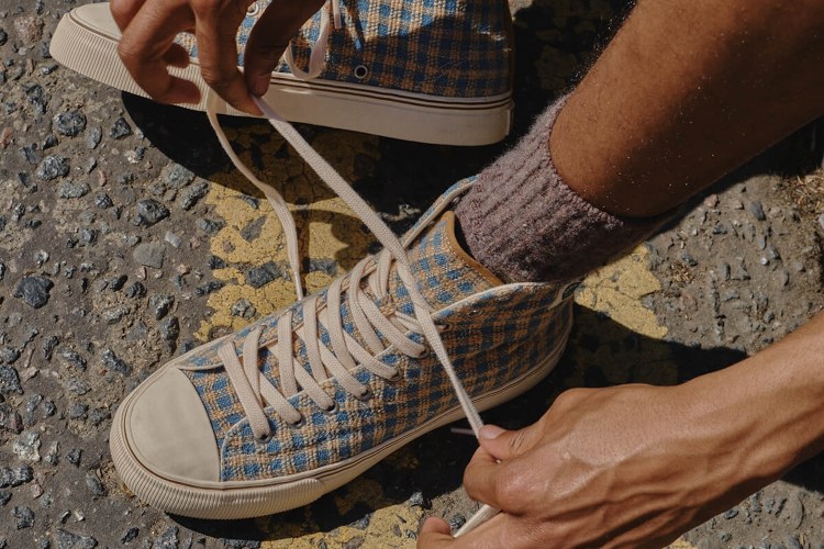 A model tying a pair of brown checked high-top sneakers.