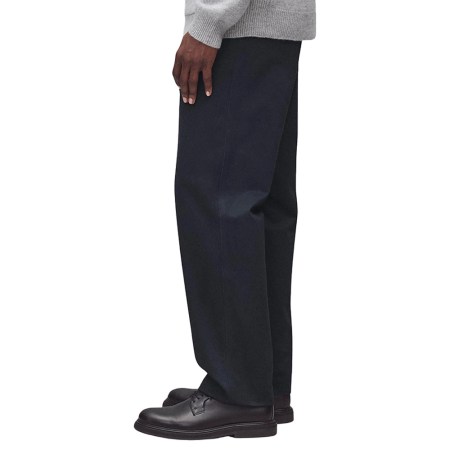 Person in a light gray sweater and dark blue pants, with dark brown shoes, standing in profile.