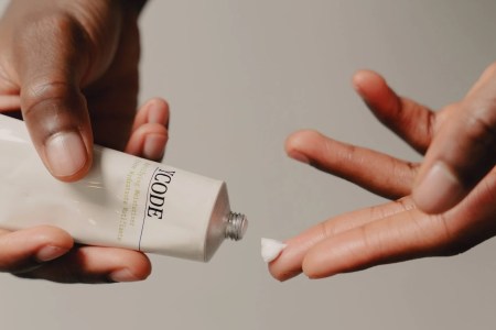 a model's hands squeezing YCode moisturizer out of a tube onto their fingers