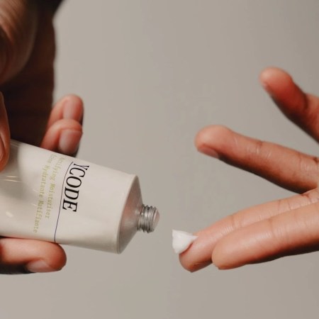 a model's hands squeezing YCode moisturizer out of a tube onto their fingers