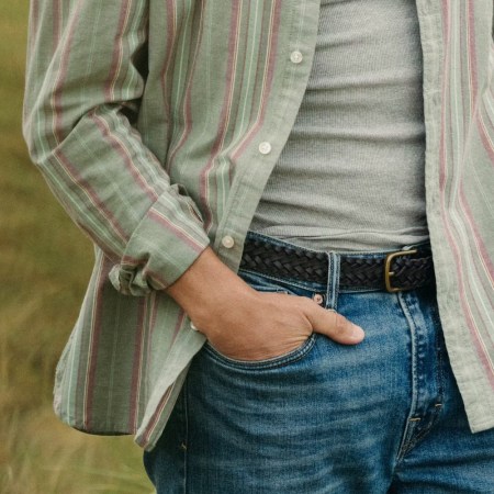 a model in a grey tank top, blue jeans and an open green button up