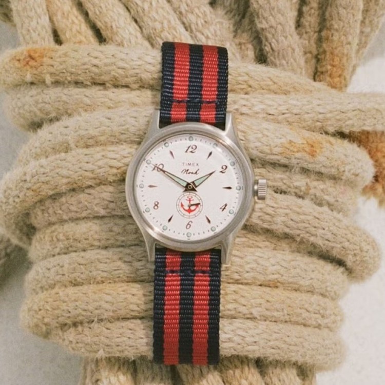 Silver watch with a cream face, red anchor logo, and a red and navy striped fabric strap.