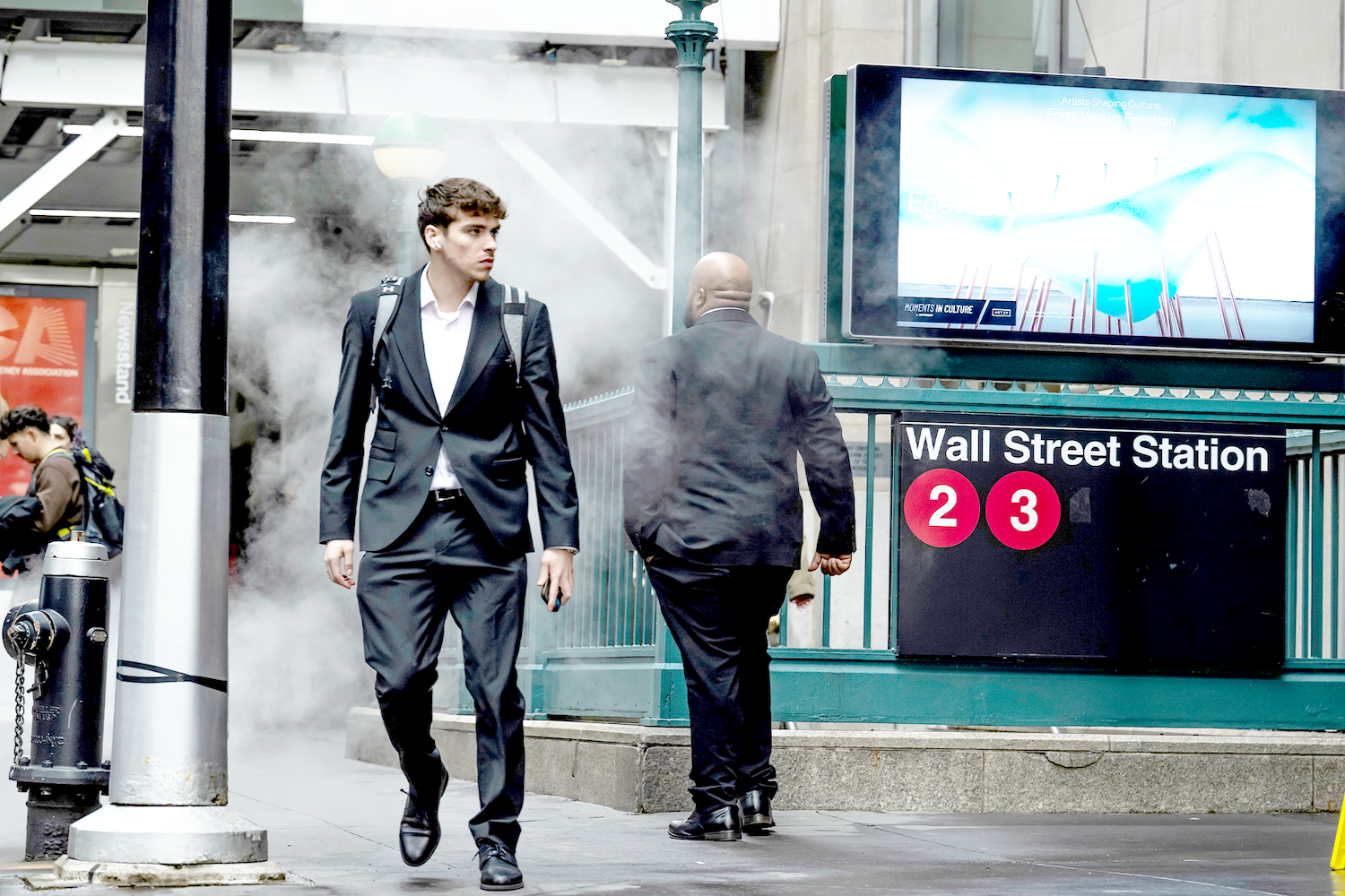 A man in a suit walks past the 2/3 line subway station at Wall Street