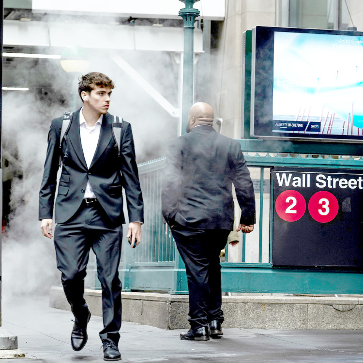 A man in a suit walks past the 2/3 line subway station at Wall Street