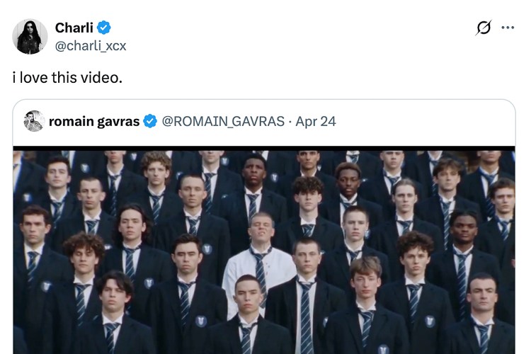 A screenshot of a tweet from Charli XCX featuring an image of a large group of young men in dark blazers and striped ties, one man in a white shirt stands out.