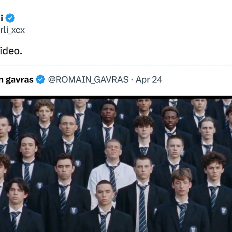 A screenshot of a tweet from Charli XCX featuring an image of a large group of young men in dark blazers and striped ties, one man in a white shirt stands out.