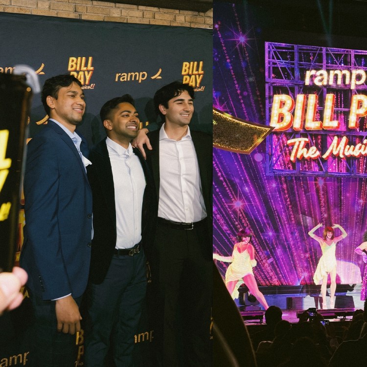 Three men pose on a red carpet next to a stage with performers and a "Ramp Bill Pay The Musical!" sign.