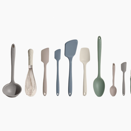 A collection of ten kitchen utensils, including a ladle, whisk, spatulas, spoons, and a peeler, in muted colors.