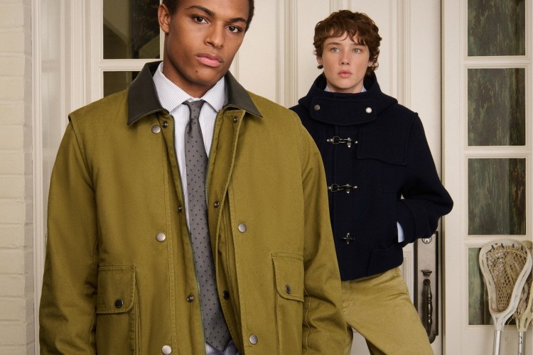 Two young men in fall coats: one in olive green with a tie, another in a navy duffle coat.