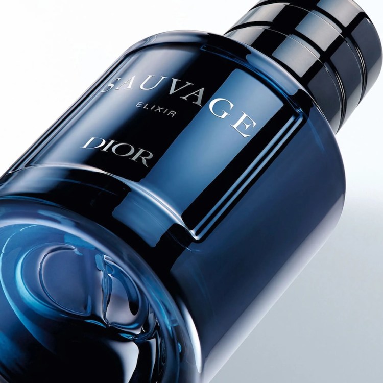 A dark blue glass bottle of Dior Sauvage Elixir cologne, tilted on a white background, with a black ribbed cap.