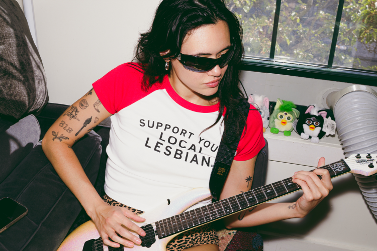 rivkah reyes wearing sunglasses playing a guitar with furbies in the background
