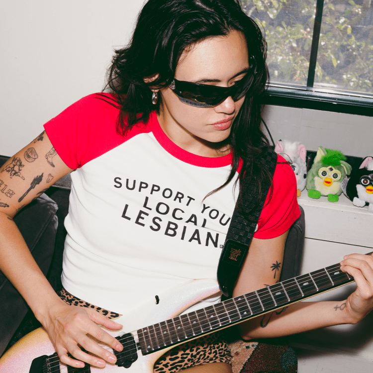 rivkah reyes wearing sunglasses playing a guitar with furbies in the background