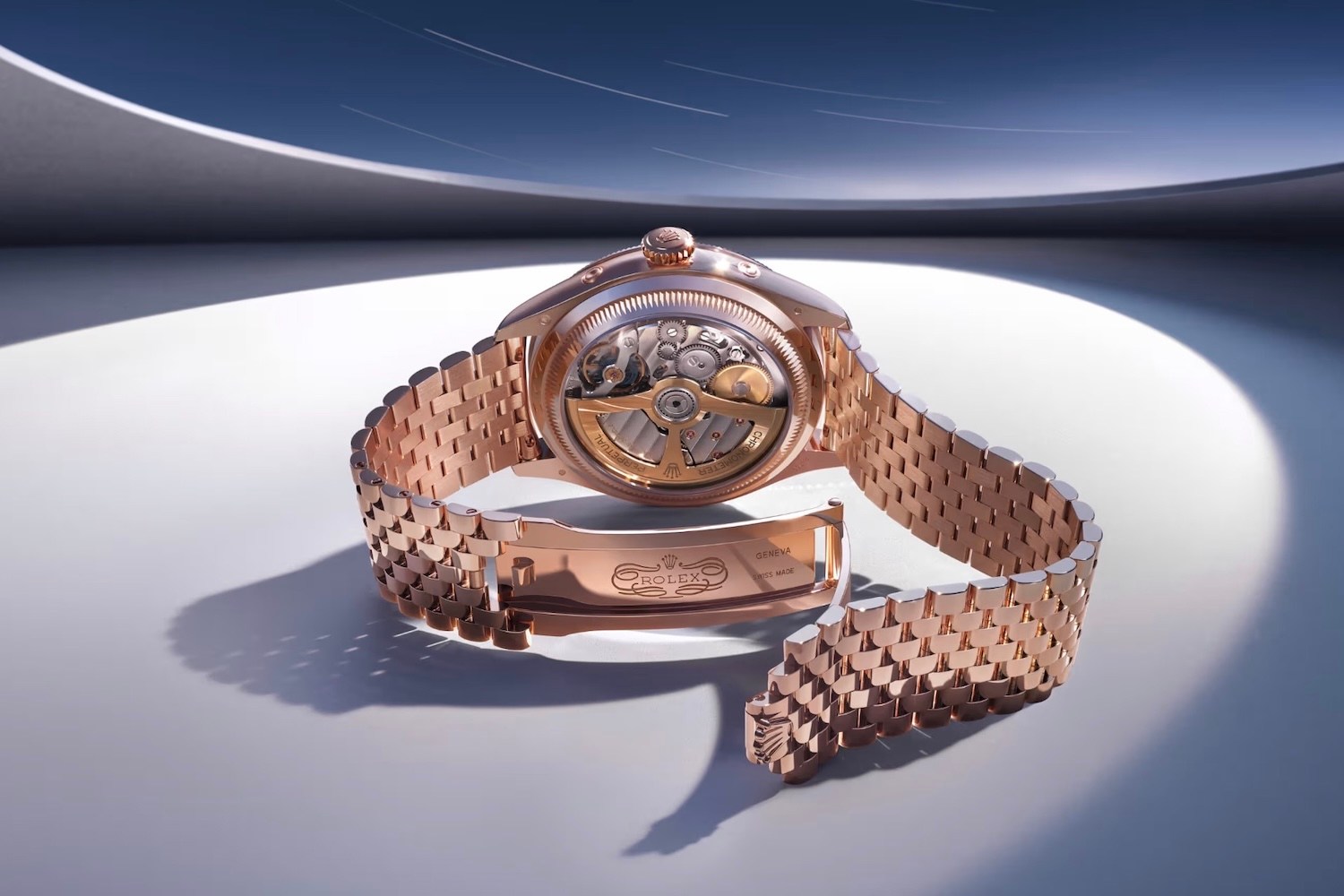 Rose gold Rolex watch with an open back revealing its intricate mechanical movement, set against a modern, curved backdrop.
