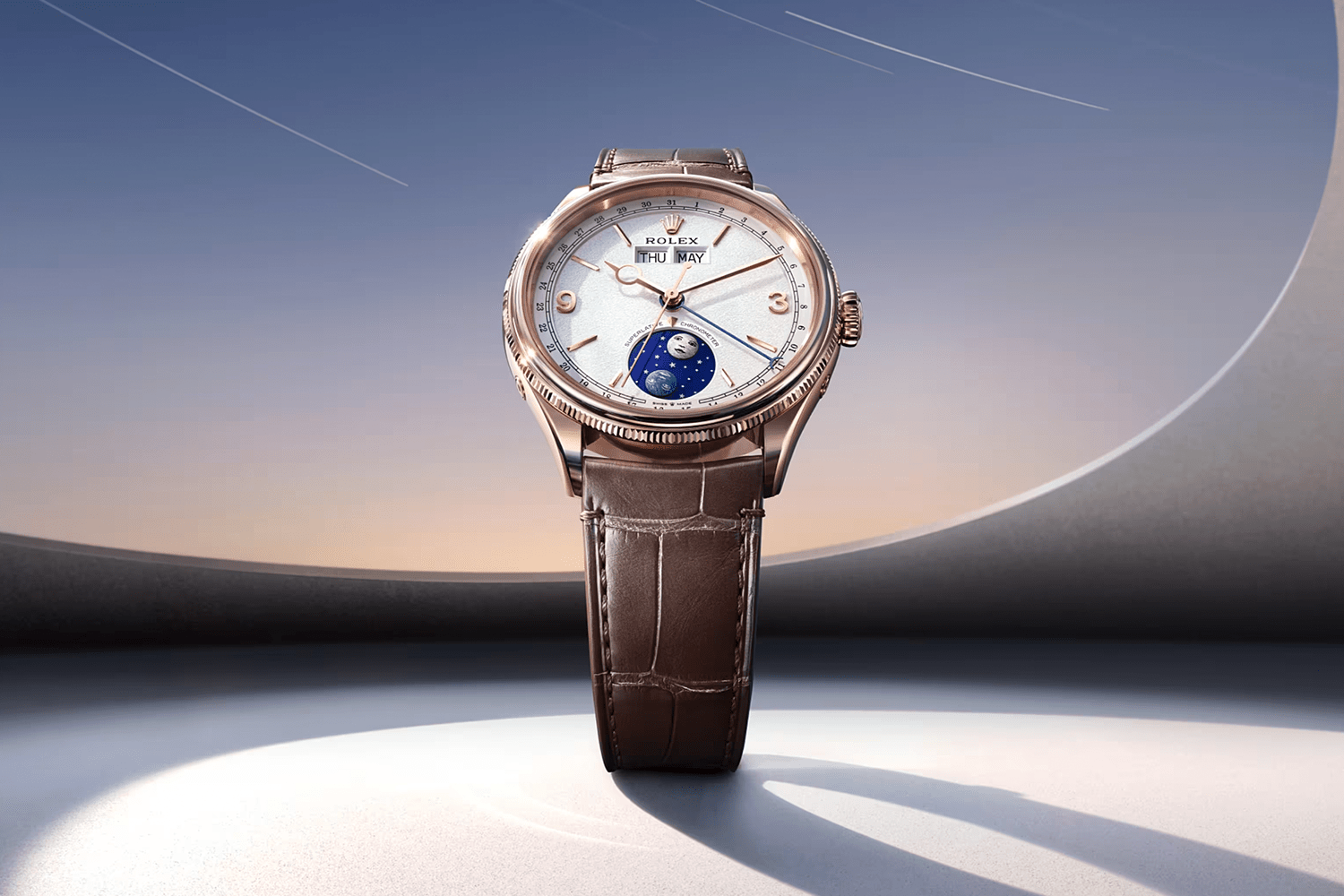 Rose gold Rolex Cellini Moonphase watch with a white dial, brown leather strap, and a moon phase indicator.