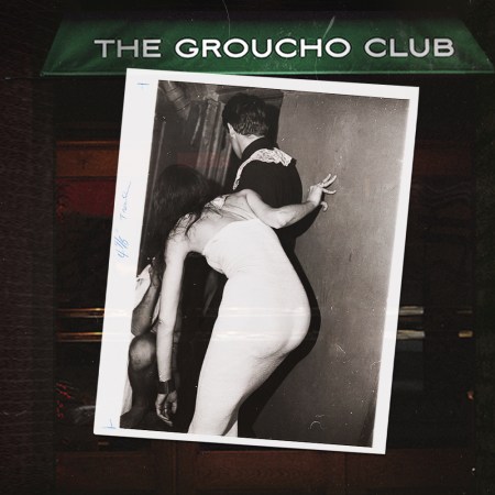 Black and white photo of a woman in a white dress peering around a corner with a man, set against a dark background with "THE GROUCHO CLUB" banner.