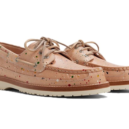 Pair of light tan boat shoes with colorful paint splatters, thick white soles, and brown trim.